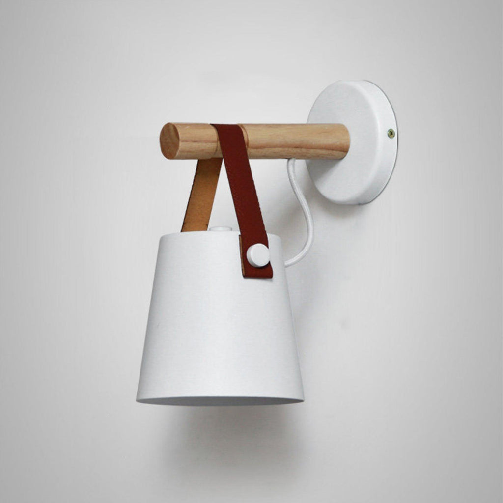 Large close view of a white Clérachic wall light on a pale grey wall, with a white cord and a brown leather strap.