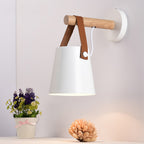 White Clérachic wall light on a pale pink wall, with a small pot of purple flowers and a dried bloom below.