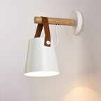Lit white Clérachic wall light on a soft pink-white wall, its opening glowing and a wooden bar above.