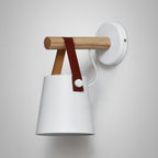 White Clérachic wall light on a light grey wall, the wooden bar and brown strap clear against the white shade.