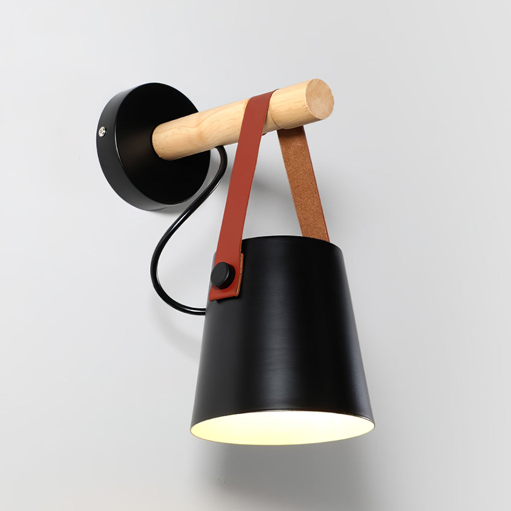 Black Clérachic wall light seen from an angle, its pale interior lit and the wooden bar pointing to the wall plate.