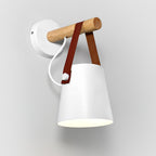 White Clérachic wall light seen from an angle on a light wall, with a white cord and a red-brown leather strap.