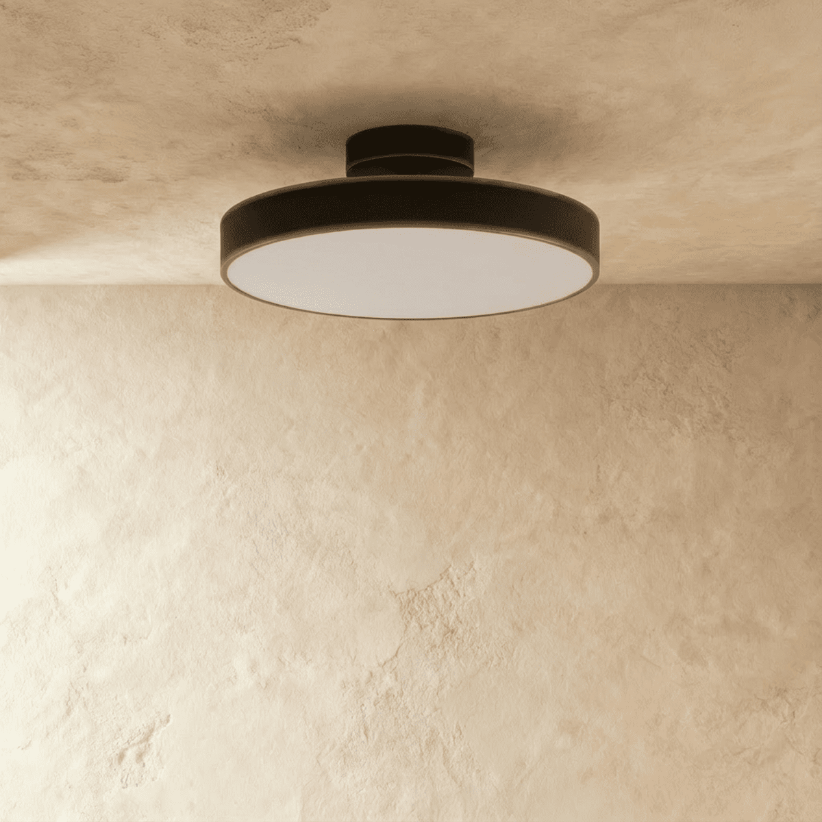 Clérachic black flush-mount ceiling light casting a soft warm glow from its round frosted lens in a plain room.