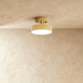 Clérachic copper-finish flush ceiling light with a warm frosted disc, mounted close against a plaster ceiling.