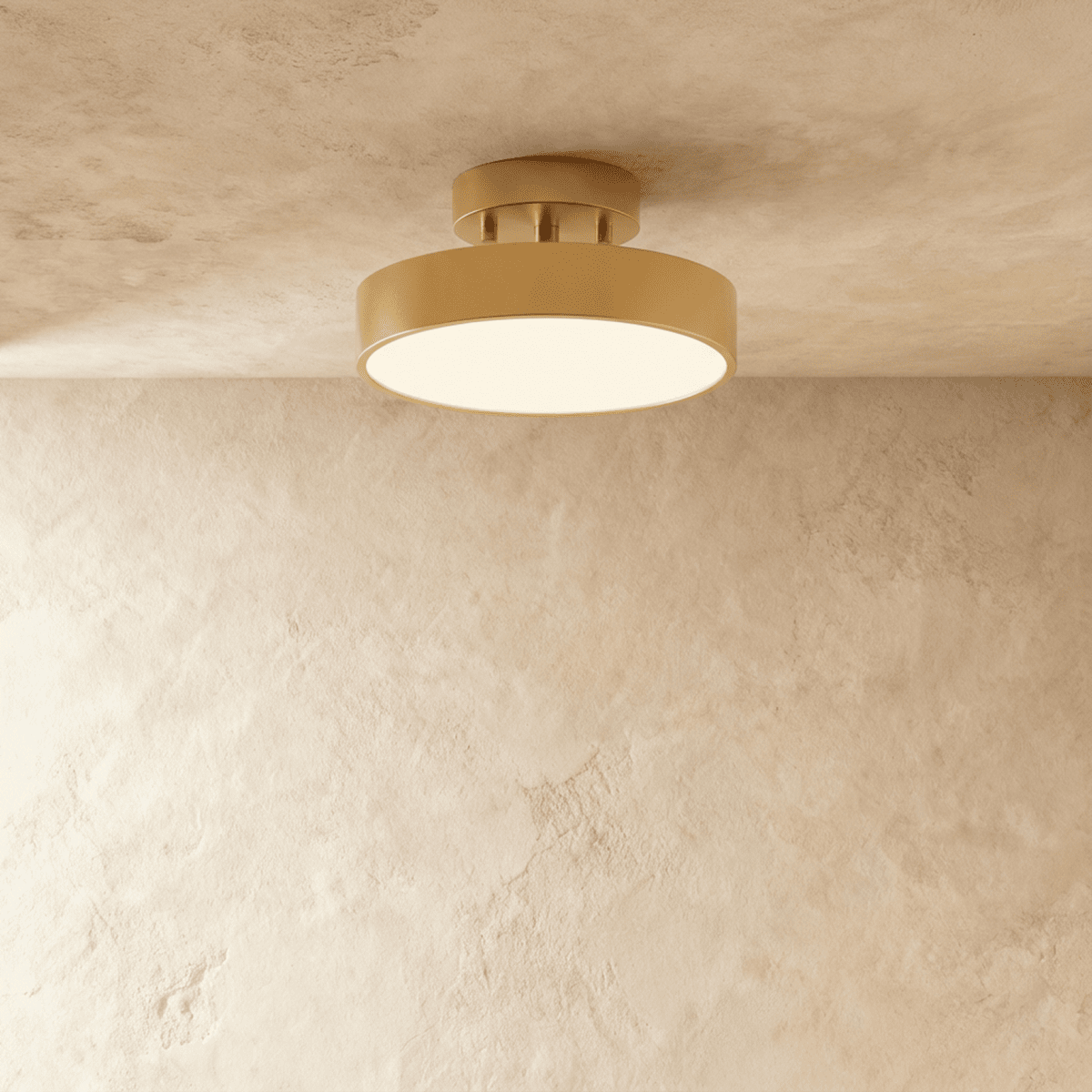 Clérachic copper flush-mount ceiling light glowing warmly, its brass drum shade set against a plain plaster wall.
