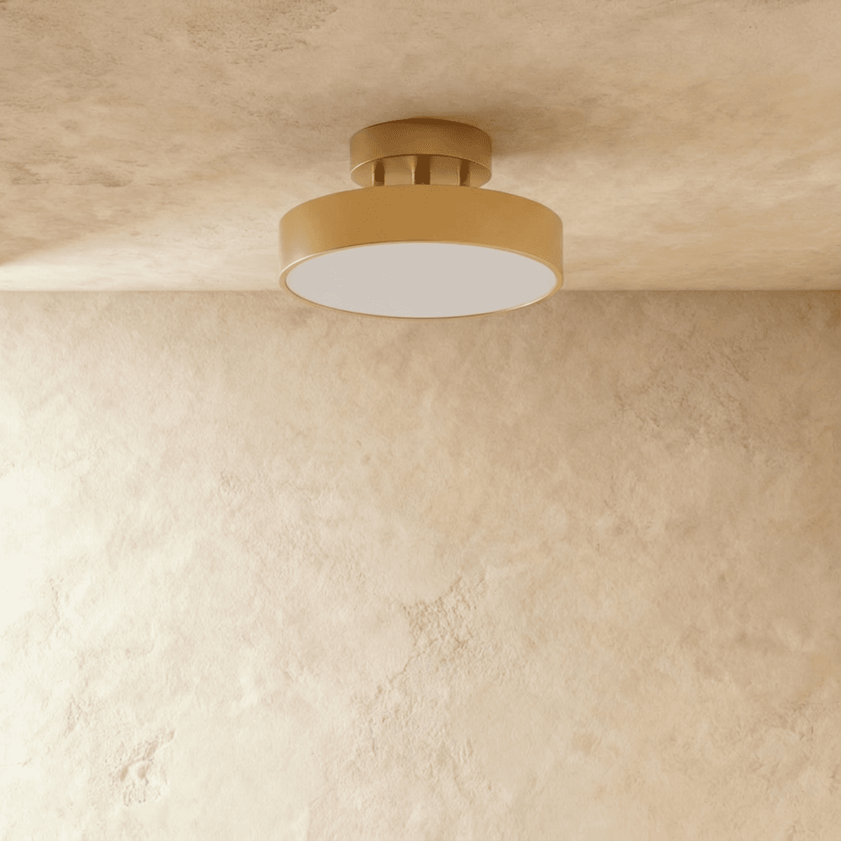 Clérachic copper flush ceiling light shown close, its brass drum and frosted disc glowing against a beige wall.