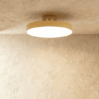 Clérachic copper-finish flush-mount light with a wide frosted diffuser, centred on a plain plaster ceiling corner.