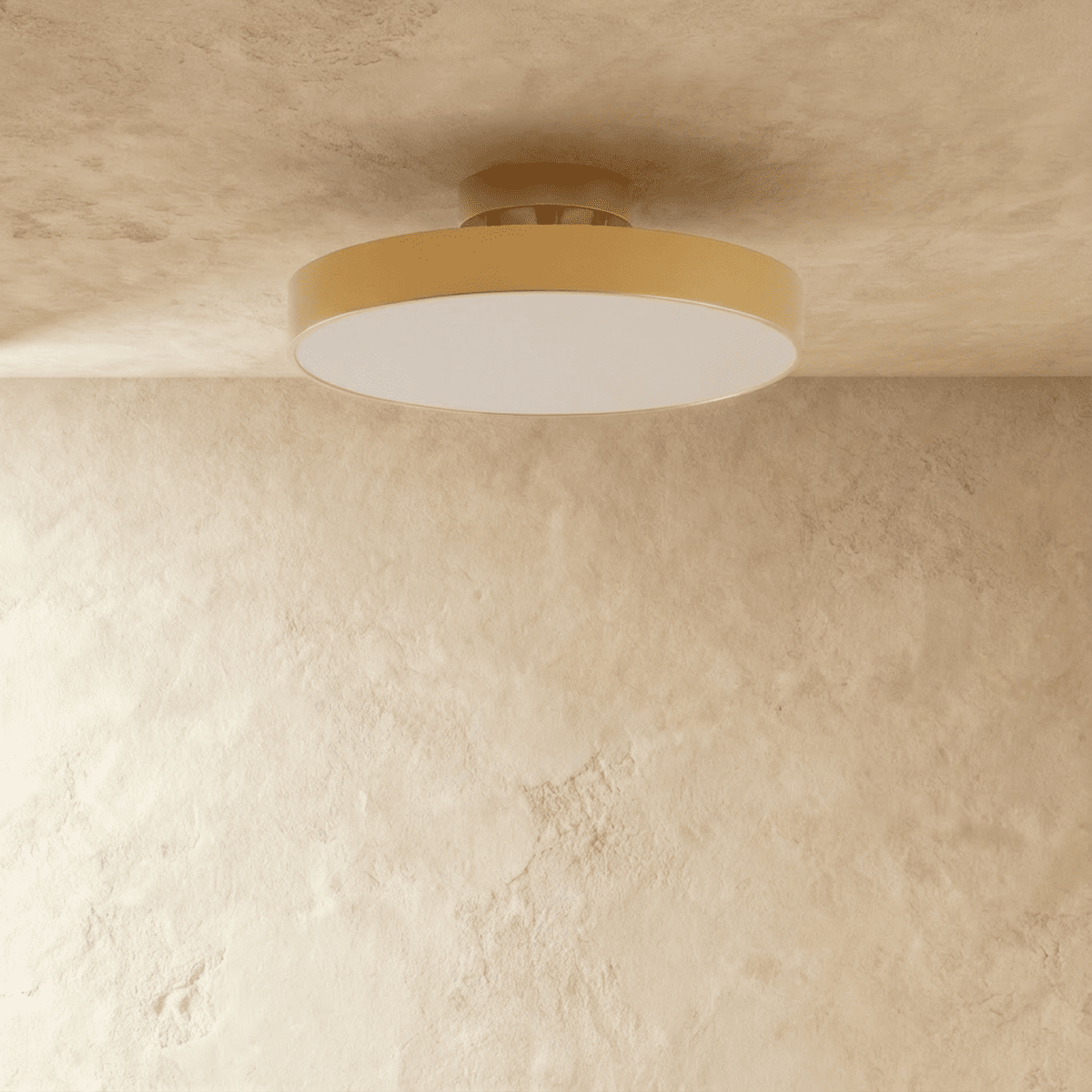 Clérachic copper ceiling light glowing warm, its brass drum shade mounted flush where wall meets plaster ceiling.