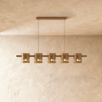 Clérachic linear chandelier with five amber glass cylinder shades along a slim bronze bar.