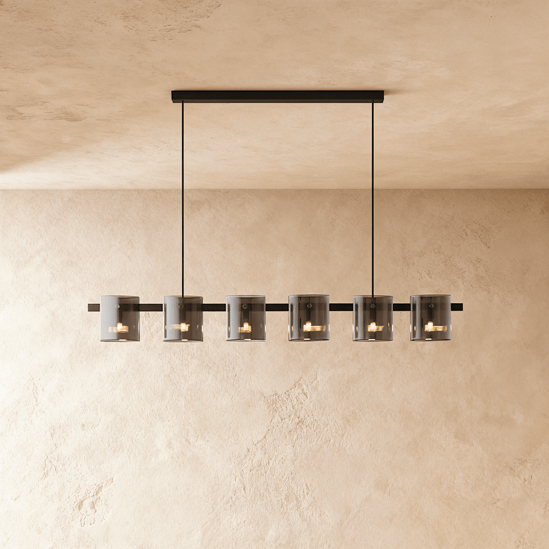 Clérachic linear chandelier with six smoky glass cylinder shades along a slim black bar, against a plaster wall.