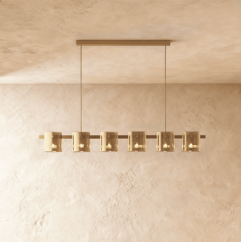 Clérachic linear chandelier with six amber glass cylinder shades along a slim bronze bar, each lit softly within.