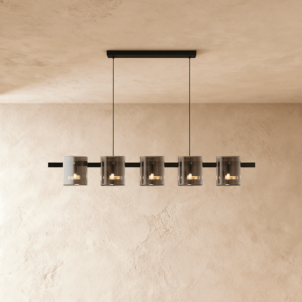 Clérachic linear chandelier with five smoky glass cylinder shades along a slim black bar, each lit softly within.