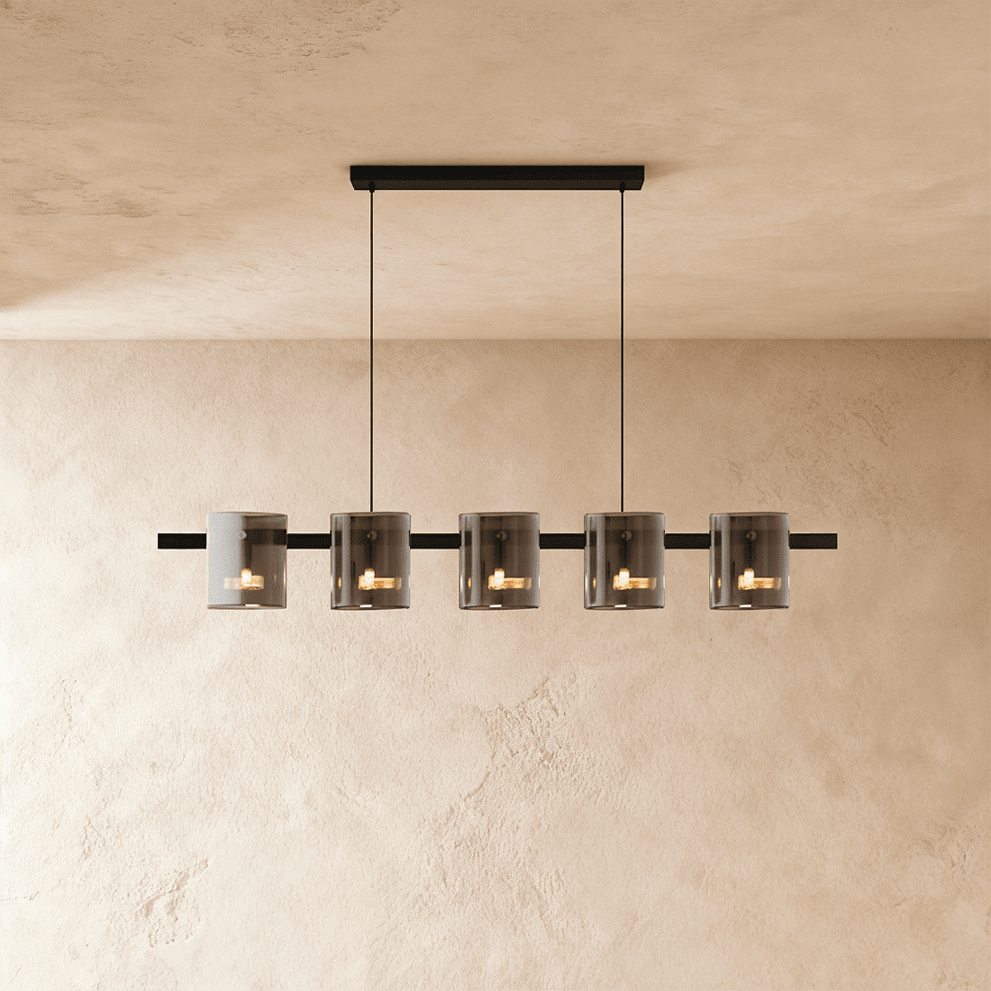 Clérachic linear chandelier with five smoky glass cylinder shades along a slim black bar, each lit softly within.