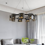 A Clérachic chandelier in dark smoky glass hangs low above a grey sectional sofa and sheer curtains.