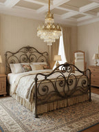 Clérachic chandelier lit over a wrought-iron bed with floral bedding, in a striped-wall room with a coffered ceiling.