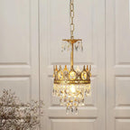 Smaller single-tier Clérachic crystal chandelier hung on a chain in front of white panelled doors, with a bare branch at left.
