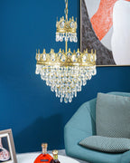 Clérachic crystal chandelier hung against a deep blue wall with an abstract print, a teal armchair below.
