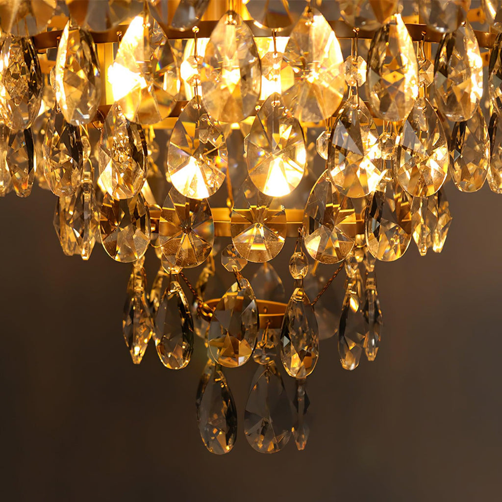 Close view of the lit clear crystal drops and tiered rings on this Clérachic chandelier, glowing amber against a dark wall.