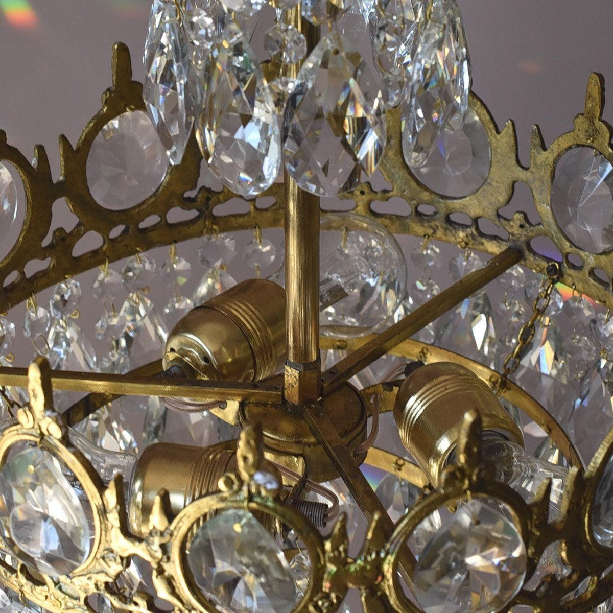 Close view of the brass bulb holders and arms inside the crown-edged ring of this Clérachic chandelier.