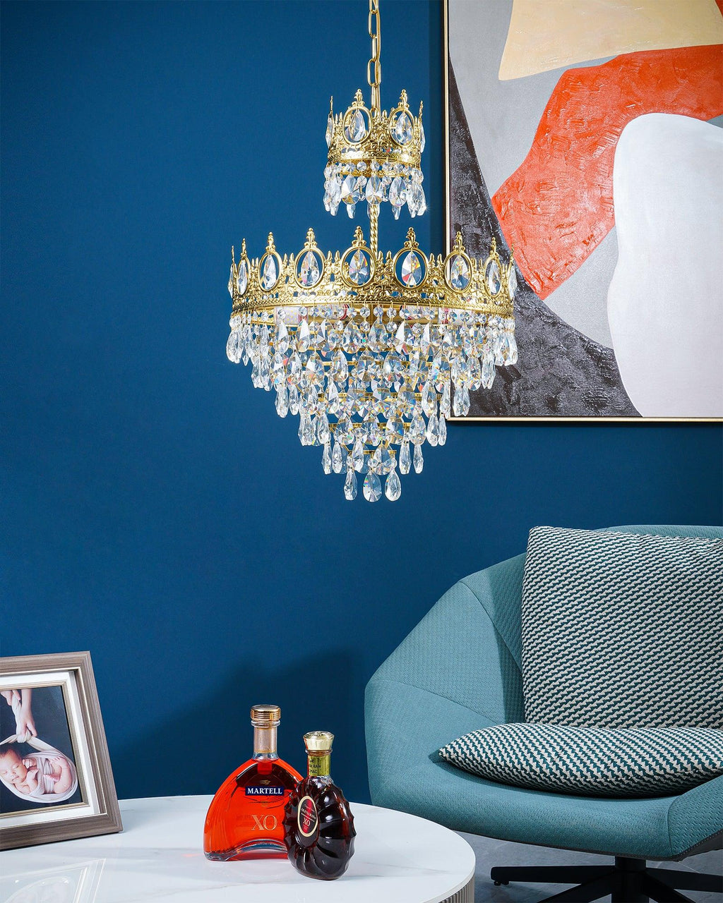Clérachic crystal chandelier hung in front of a blue wall with an abstract print, with a teal chair and a table below.