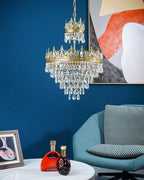 Clérachic crystal chandelier hung in front of a blue wall with an abstract print, with a teal chair and a table below.