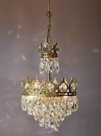 Smaller Clérachic chandelier hung on a chain against a mauve backdrop, with a small crown tier above a short crystal skirt.