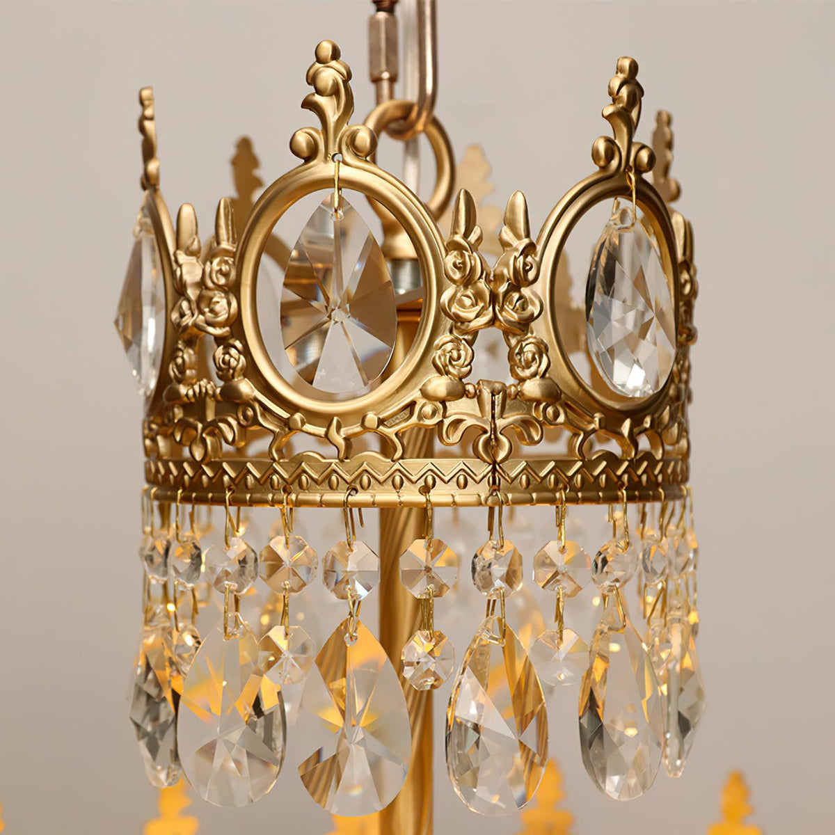 Close view of the cast crown ring with rose details and the hanging crystal drops on this Clérachic chandelier.