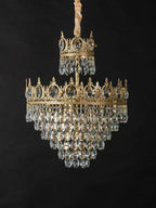 Clérachic crystal chandelier on a black backdrop, with a gold-wrapped chain, a small crown tier and a larger tiered skirt.