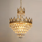 Lit Clérachic chandelier against a beige backdrop, its crown tiers glowing above layered teardrop crystals.