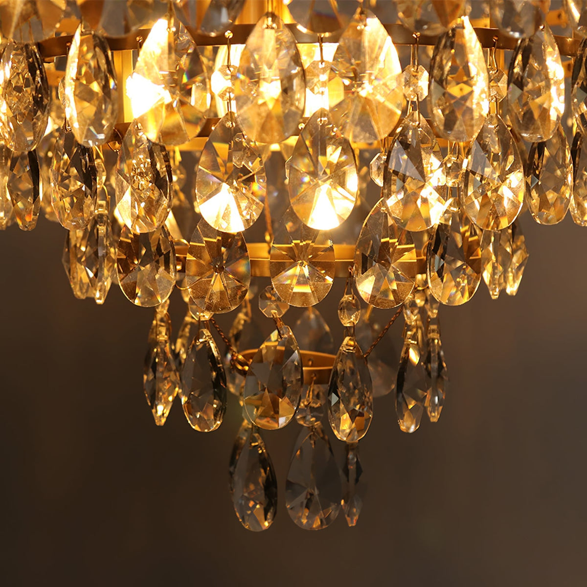 Close view of the lit lower tiers of this Clérachic chandelier, with amber light through the crystal drops.