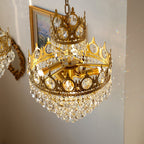 View from below of a lit Clérachic chandelier, showing its brass bulb holders inside the crown ring and crystal skirt.