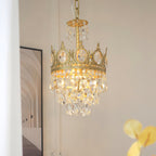Smaller Clérachic chandelier lit on a pale wall, in front of a framed arched-corridor print, with a yellow leaf at right.