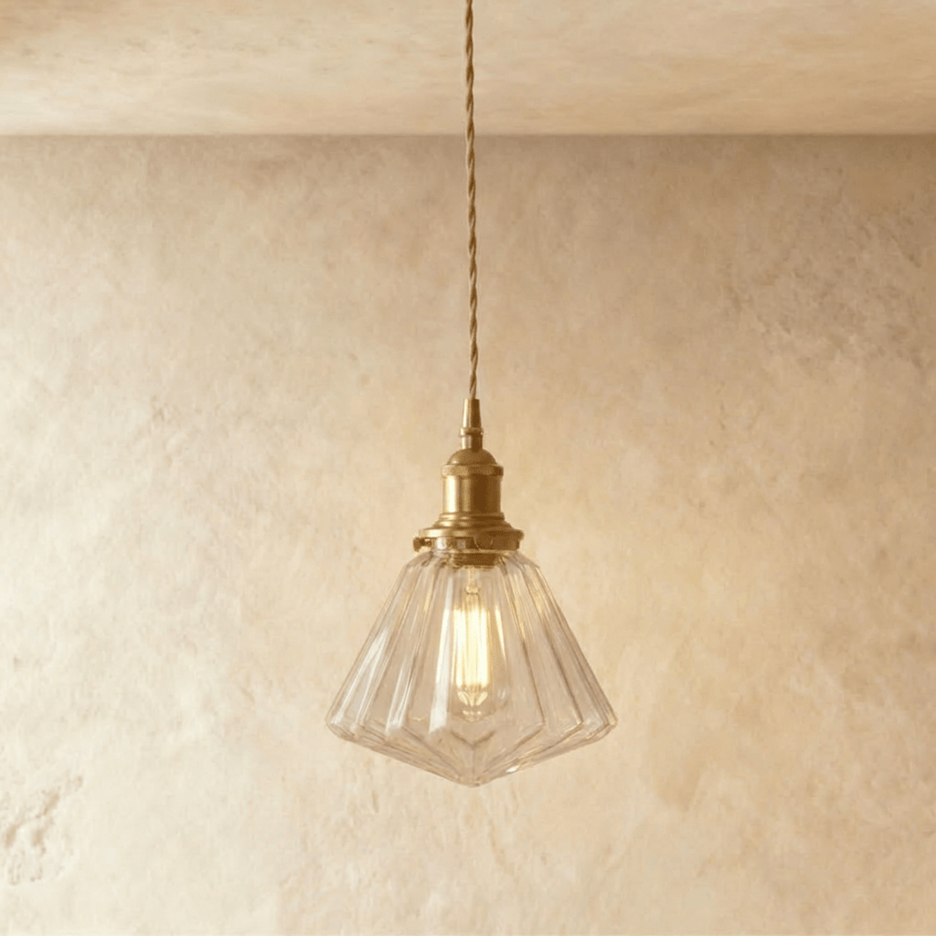 Clérachic Isabel pendant light, a faceted geometric clear glass cone shade catching light on angled brass fitting.