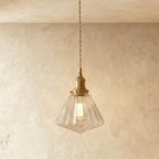 Clérachic Isabel pendant light, a faceted geometric clear glass cone shade catching light on angled brass fitting.