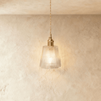 Clérachic Isabel pendant light, a tapered clear glass cone shade with fine vertical ribbing glowing warm white.