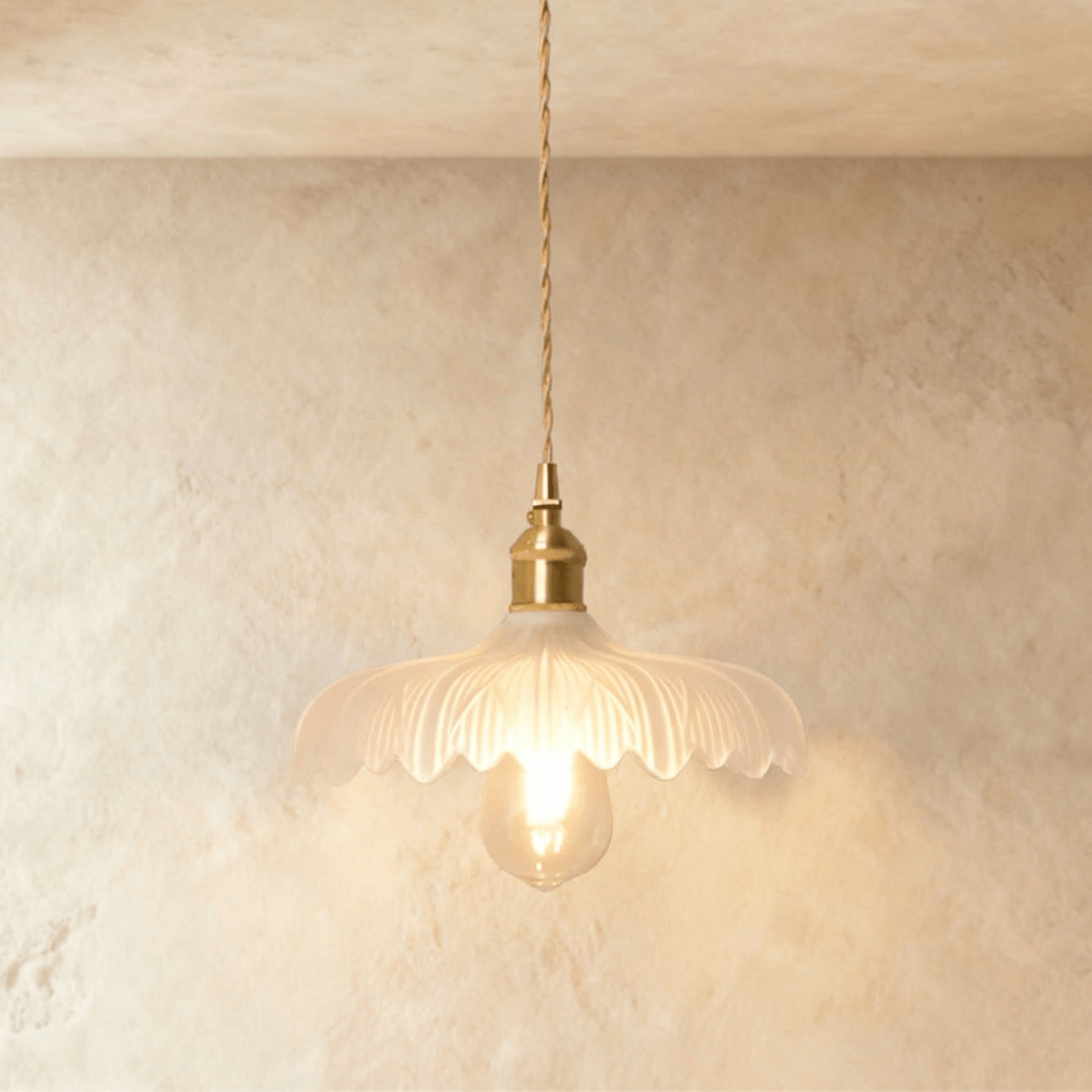 Clérachic Isabel pendant light, a ruffled clear glass flower shade with pointed scalloped petals and an exposed bulb.
