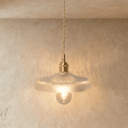 Clérachic Isabel pendant light, a wide clear glass dome shade with a woven grid texture glowing warm on brass.