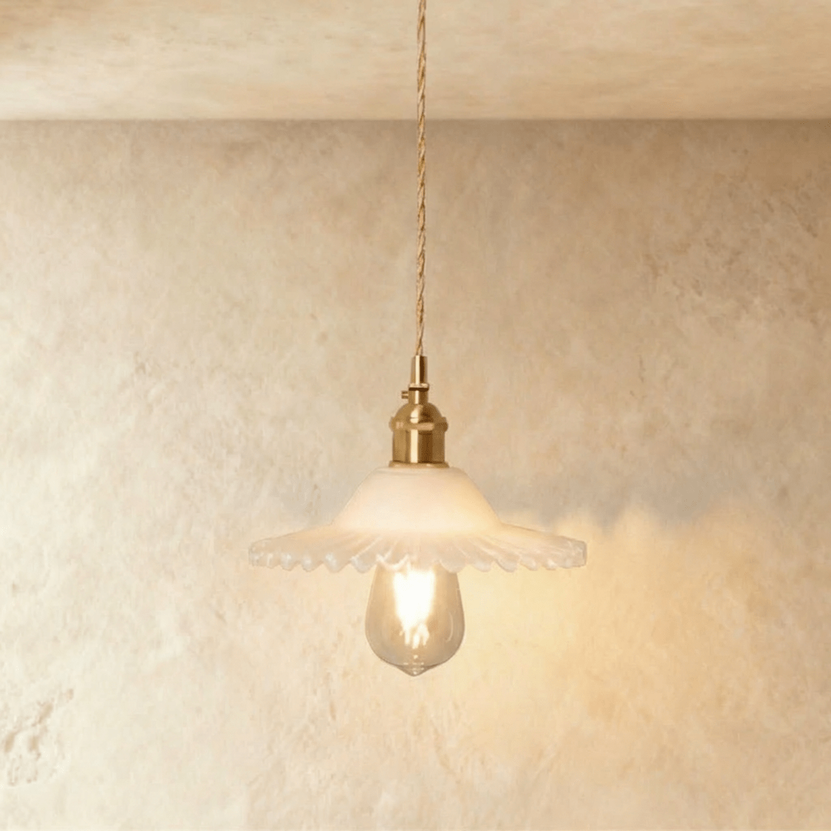 Clérachic Isabel pendant light, a ruffled opal white glass flower shade glowing softly around an exposed bulb.