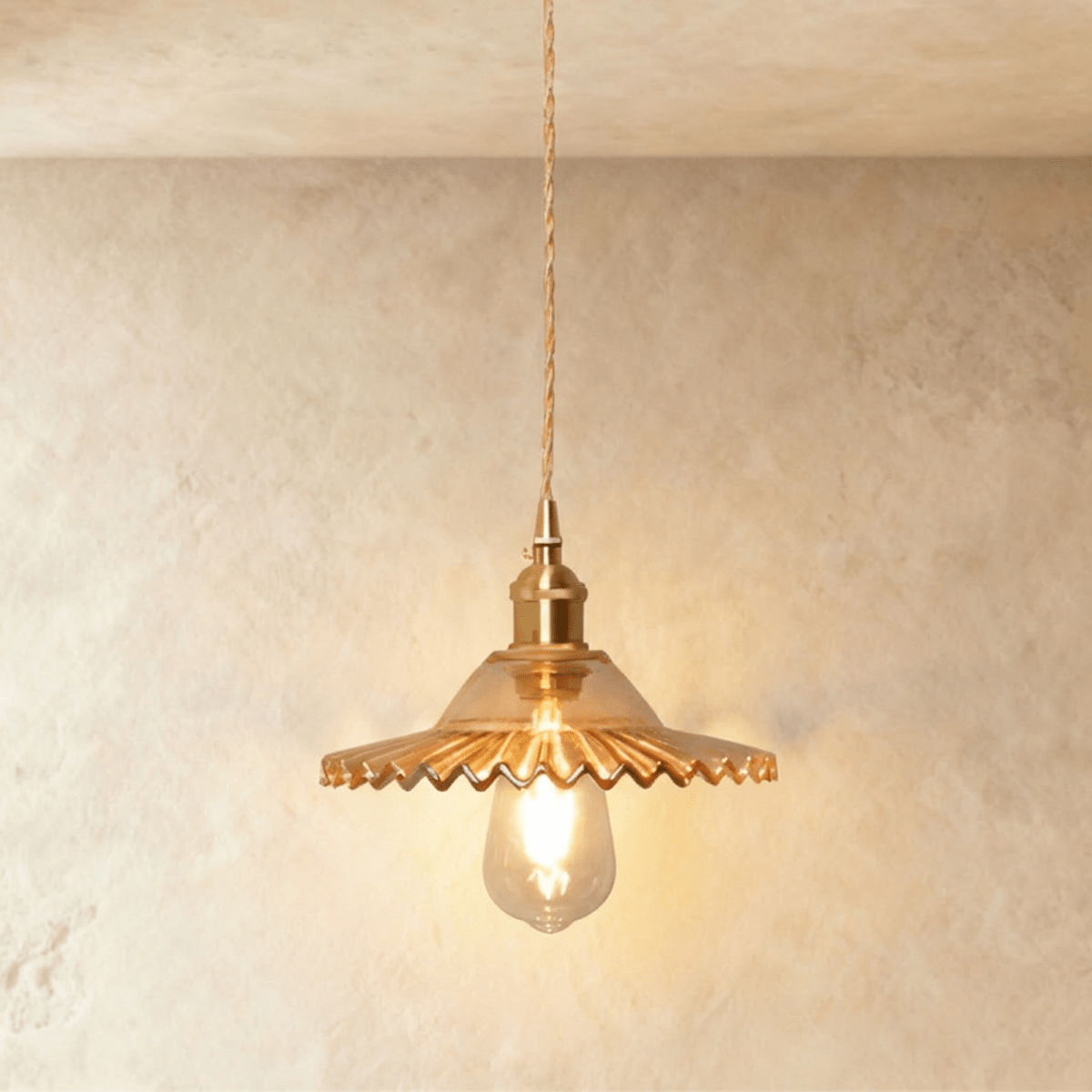 Clérachic Isabel pendant light, a ribbed amber-tinted glass saucer shade glowing warm around an exposed bulb.