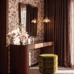 Two Clérachic Isabel pendant lights, one ribbed and one grid-textured, hang beside a walnut vanity with floral wallpaper.