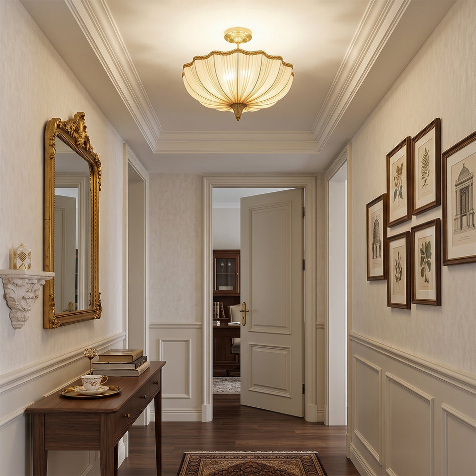 A Clérachic ceiling light in a panelled hallway with a gilt-framed mirror, a dark wood console and a gallery of botanical prints.