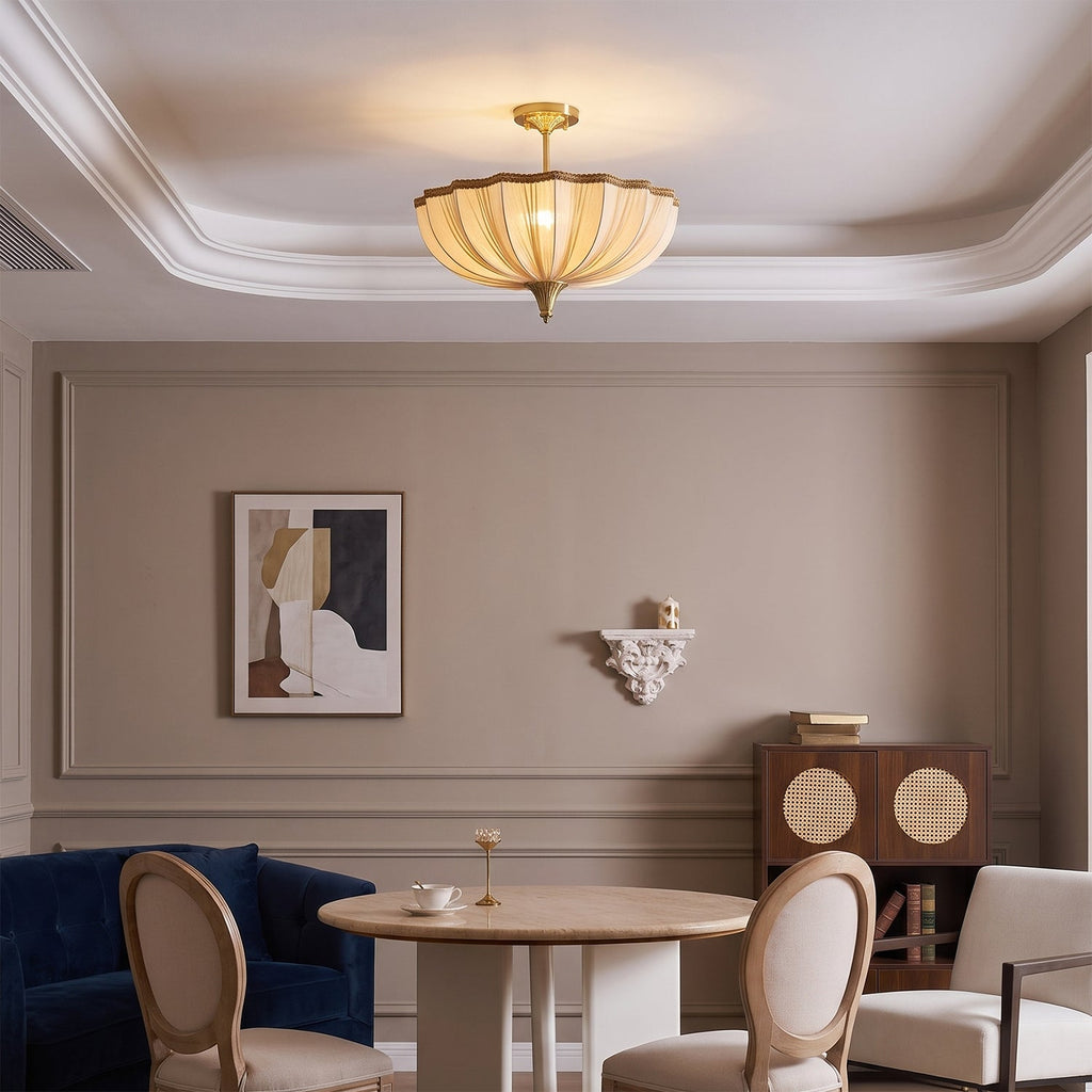 Clérachic ceiling light glowing above a taupe dining room with a round pale table, cane-backed chairs and a navy armchair.