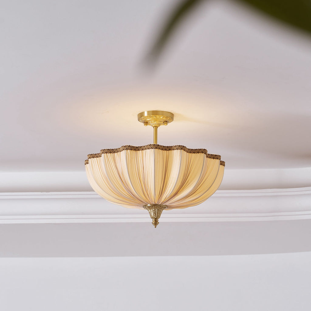 View from below of the Clérachic ceiling light on a white ceiling with a cornice, lit warm, with a leaf blurred at the top edge.