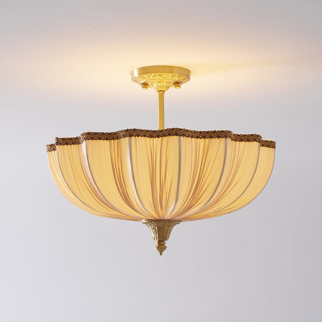 The Clérachic ceiling light lit on a pale ceiling, with a longer view of its brass stem and a warm glow above the shade.