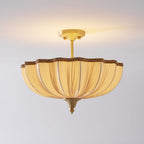 The Clérachic ceiling light lit on a pale ceiling, with a longer view of its brass stem and a warm glow above the shade.