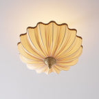 Clérachic ceiling light from a low angle, lit, showing the underside of the pleated shade fanning out from its brass finial.