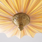 Close view up into the base of the Clérachic ceiling light, with a carved brass finial where the pleats meet.