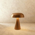 Clérachic copper table lamp with a curved dome shade and cone base, lit warm against a limewash wall.