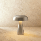 Clérachic silver table lamp, its brushed dome shade and tapered base lit warm on a limewash backdrop.