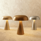 Clérachic mushroom-shaped table lamps in gold, copper and silver finishes, lined up against a limewash wall.